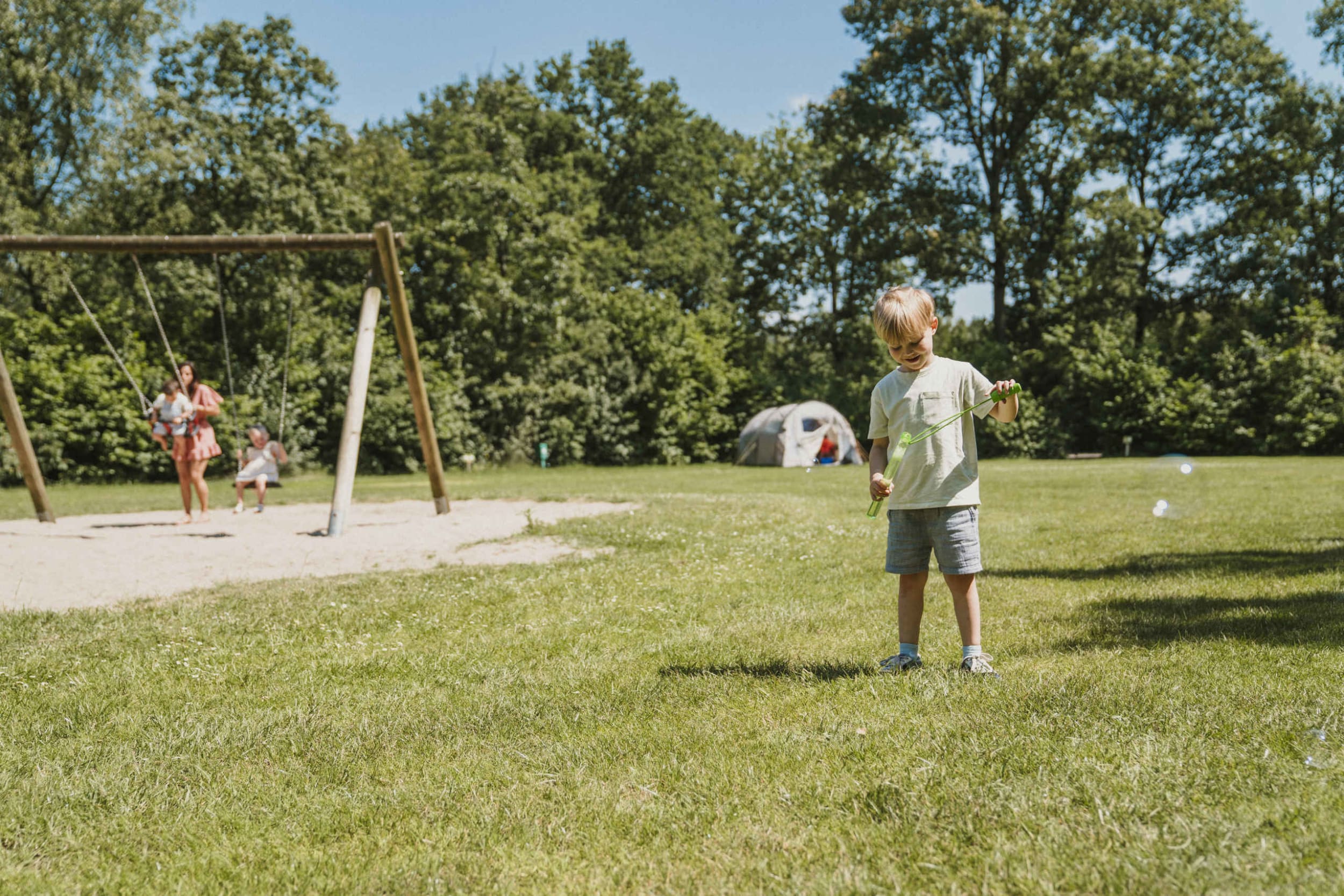 kampeerplaats-schommel-speeltuin-jongen-bellenblaas-kamperen-vakantiepark-dierenbos